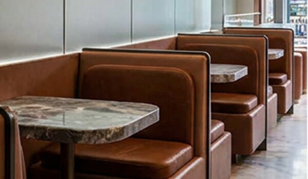 Cinnavibes Four empty brown leather booths with marble tables are lined up against a wall in Cinnamon Deserts Café, creating the perfect cosy spot to enjoy signature cinnamon rolls and soak in the inviting Cinnavibes. Cinnamon Rolls
