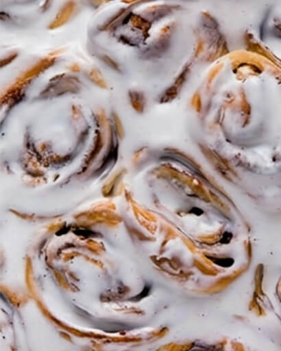 Cinnavibes Close-up of several Cinnavibes cinnamon rolls covered in white icing, freshly baked at Cinnamon Desserts Café. Cinnamon Rolls