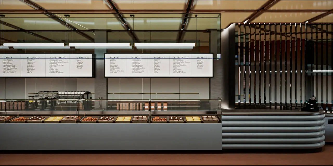 Cinnavibes Modern bakery counter with glass display of assorted pastries, chocolates, and signature Cinnamon Rolls from Cinnamon Deserts Café. A coffee machine sits on the left, whilst menu boards featuring the latest Cinnavibes hang above against a backdrop of glass and wood panelling. Cinnamon Rolls